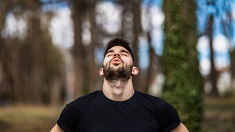 Man breathing in forest with head back and eyes closed