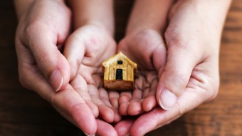 Hands holding a small house