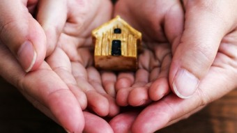 Hands holding a small house