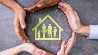 Hands surround image of a house with people inside